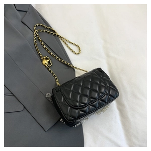 Close-up of black quilted leather bag with gold chain strap and metal ball adjuster
