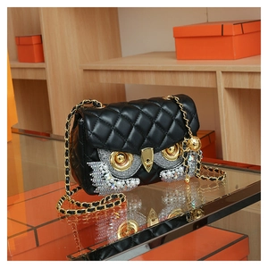 Detailed view of owl-eye design featuring sparkling rhinestones and pearls on black leather