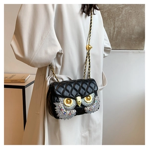 Detail of owl buckle with rhinestones and pearls on black quilted shoulder bag