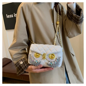 Detailed close-up of white quilted bag with owl jewel embellishment and gold chain