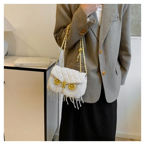 Detailed view of white quilted owl bag with sparkling bead tassels and gold chain