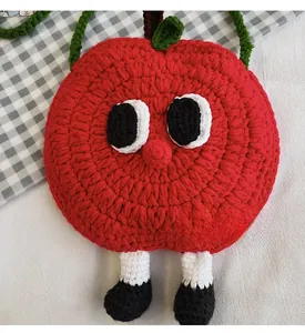 Detailed view of handmade red apple crochet bag with 3D cartoon legs and green strap
