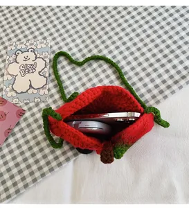 Detail of red strawberry crochet bag showing interior capacity for phone and cosmetics