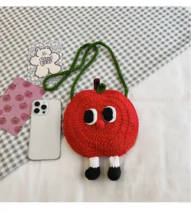 Close-up of handmade red apple crochet purse with cute big eyes and green strap