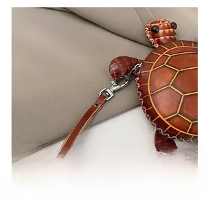 Détail du mignon petit sac tortue en cuir avec crochet métallique et fines coutures jaunes