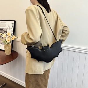 Fashionable black bat-shaped PU leather crossbody bag worn by model in minimalist indoor setting