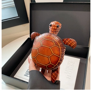 Détail d'un porte-monnaie en cuir en forme de tortue avec coque texturée et coutures
