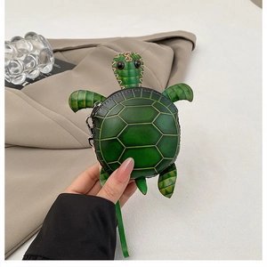 Détail du porte-monnaie tortue verte avec coutures de carapace et dragonne zippée
