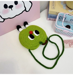 Close-up of handmade green knitted apple coin purse with cartoon face and long strap