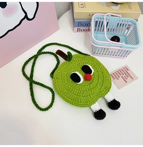 Close-up of handmade knitted green apple crossbody bag with cute cartoon character details