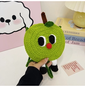 Detail of green handmade knitted apple bag with cartoon eyes and soft yarn texture