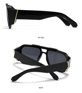 Detailansicht der schwarzen Oversize-Sonnenbrille mit breiten goldenen Metallakzenten