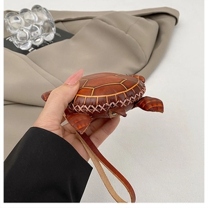 Détail d'un porte-monnaie tortue en cuir avec coque texturée et coutures faites main