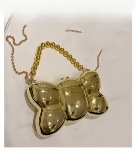 Détail du sac de soirée miroir doré avec poignée perlée et bandoulière en chaîne
