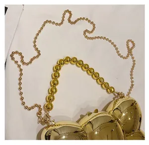 Détail du sac boîte en acrylique doré avec poignée à perles et chaîne à boules
