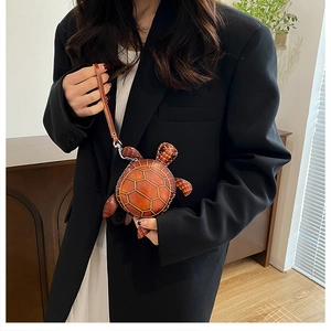Détail d'une mini pochette en cuir en forme de tortue avec surpiqûres et dragonne chic