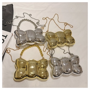 Détail de la pochette métallique en forme de nœud dorée et argentée avec perles et chaîne