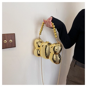 Détail d'un sac de soirée doré effet miroir avec poignée en perles et bandoulière