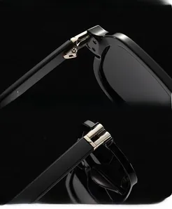 Detailed close-up of reinforced golden metal hinges on black polygon sunglasses