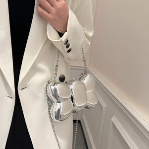Pochette nœud argenté en acrylique avec bandoulière perlée sur un blazer blanc