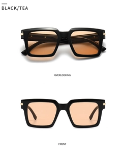 Detail view of square black sunglasses with tea lenses and gold metal hinge accents
