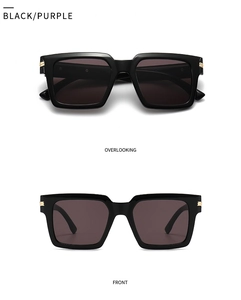 Detail view of square black sunglasses with deep purple lenses and gold metal accents