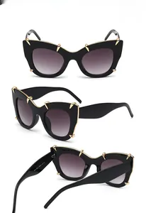 Detailed view of black oversized sunglasses with gold claw accents and gradient lenses