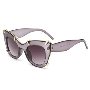 Oversized cat-eye sunglasses with translucent purple frames and gold metal claw accents