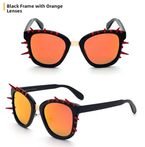 Detail of punk style sunglasses with black cat-eye frame and red conical spikes