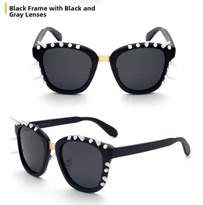 Detail view of black punk sunglasses with white studs and gold metal bridge connectors