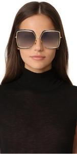 Close-up of model wearing oversized square Dita Narcissus sunglasses with gold metal frames