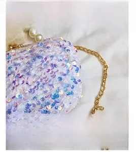 Macro view of iridescent sequins, gold metal clasp, and pearl handle on a luxury shell bag