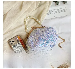 Detail of purple sequin shell bag featuring pearl handle and gold metal frame clasp