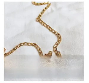 Detailed close-up of the polished gold metal chain strap for this shell handbag