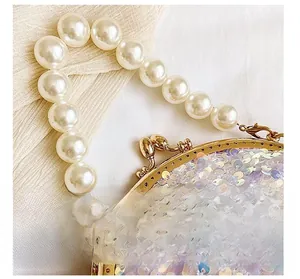 Detail of pearlescent sequins and large faux pearl handle on a luxury shell evening bag