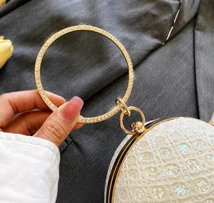 Dettaglio borsa da sera in pizzo bianco con manico ad anello dorato e strass brillanti