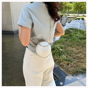 Detail of spherical evening bag with rhinestones, golden ring handle and chain strap