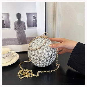 Macro shot of silver rhinestone spherical evening bag with golden metal ring handle