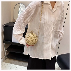 Detail of a spherical gold evening bag with woven texture and round metal top handles