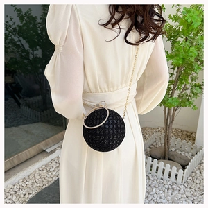 Detail of a black spherical evening bag with shimmering sequins and crystal ring handle