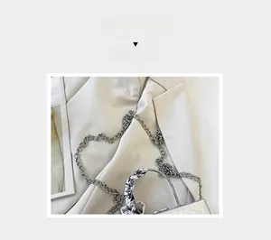 Detail of silver metallic handbag with thick chain strap and printed silk scarf handle