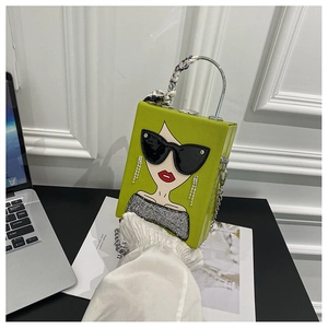 Close-up of a green box bag featuring a sunglasses lady print and silk scarf handle detail