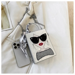 Detail of silver box bag featuring fashion lady illustration and silk scarf handle decor