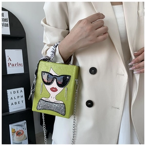 Detail of green box bag with sunglass girl print and silk scarf on handle