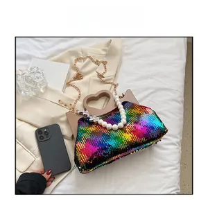 Detail of colorful sequin handbag with unique heart-shaped handle and pearl chain strap