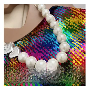 Detailed macro view of white faux pearls and silver heart charms for bag decoration