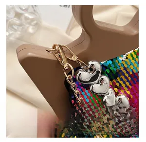 Macro shot of gold metal clasp and silver heart charms on a rainbow sequin handbag