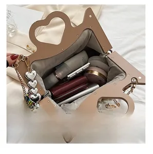 Internal capacity of khaki heart-handle bag showing phone, wallet and makeup accessories