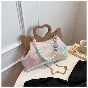 Macro shot of sequin handbag with unique heart handle and elegant pearl shoulder strap