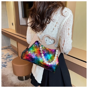 Close-up of rainbow sequin handbag featuring heart cutout handle and pearl chain detail
